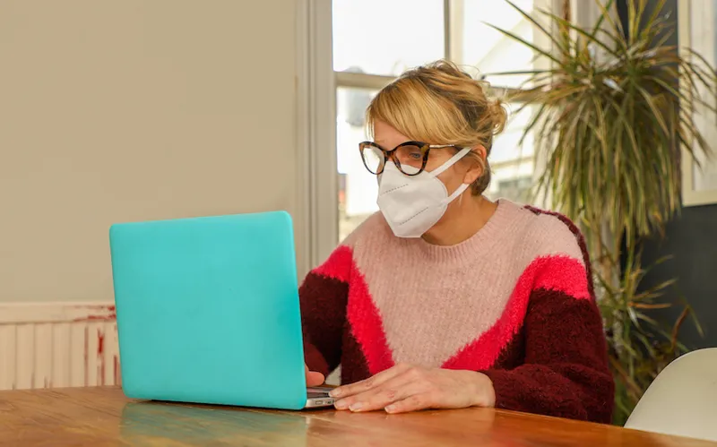 A woman wearing mask self-isolates at home