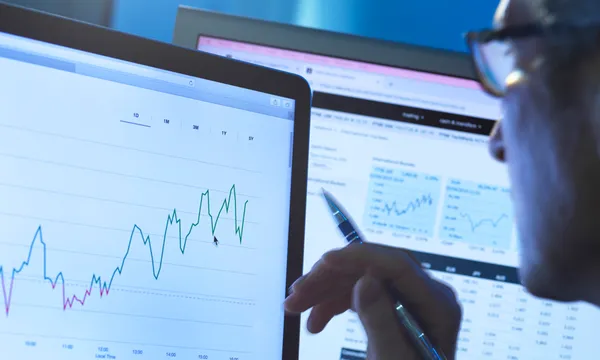 Financial services, stock analyst researching share price data of a company on the computer
