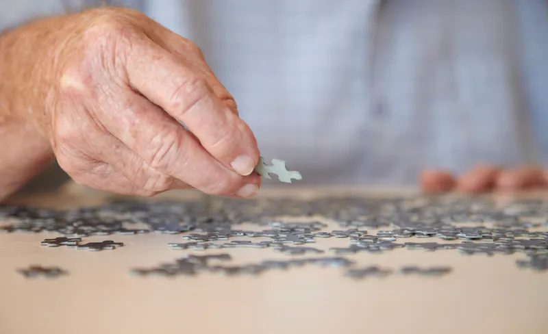Elderly man doing jigsaw puzzle