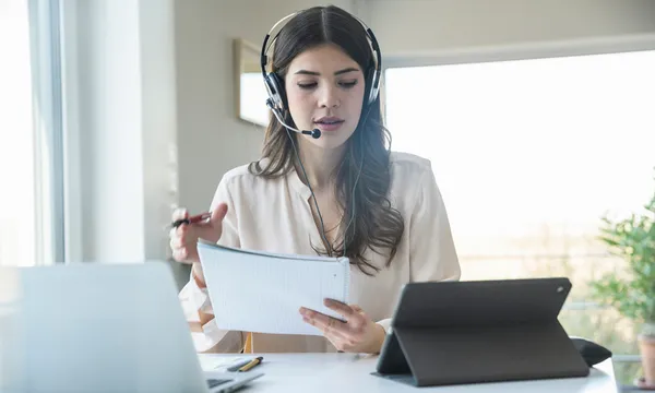 Young woman sitting at table at home wearing a headset