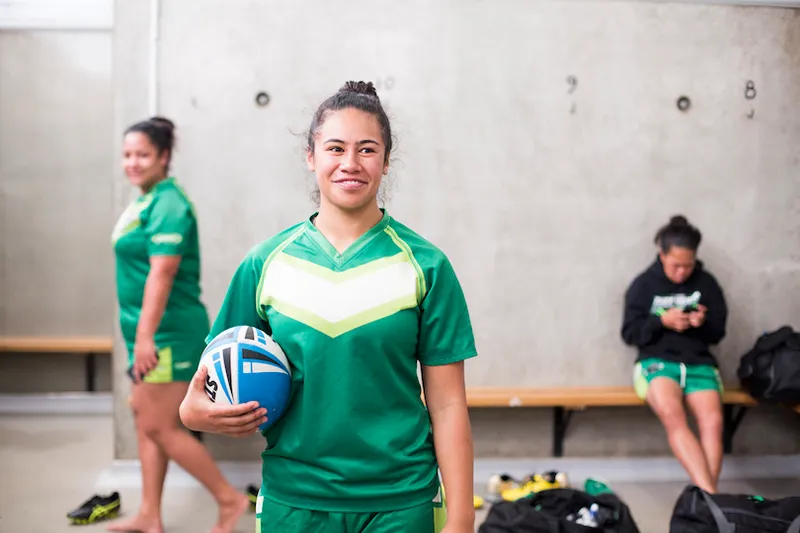 Female rugby player in changing rooms holding ball