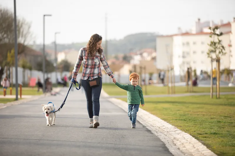 Mother and son walking with pet puppy on quiet road