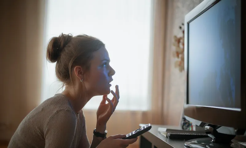 young woman looking in suspense at tv