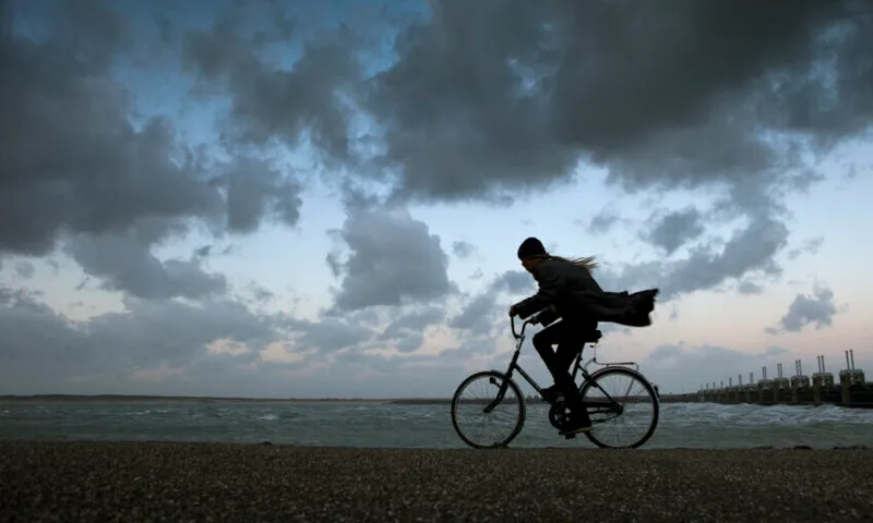 Netherlands, Kamperland. Woman Cycles During Storm