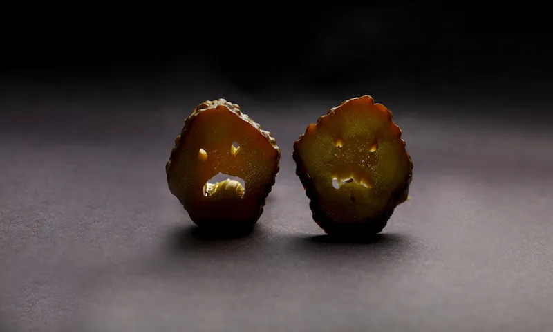 Close-Up Of Pickled Cucumber Slices On Table Against Black Background