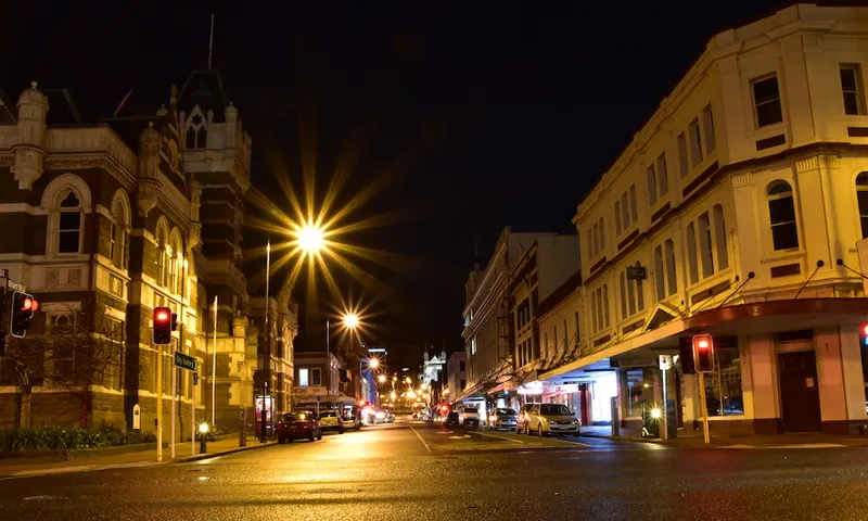 Illuminated Street Amidst Buildings In City At Night