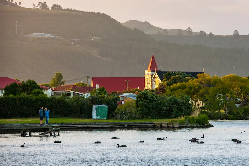 Two people standing on wooden pier by lake, Rotorua, New Zealand