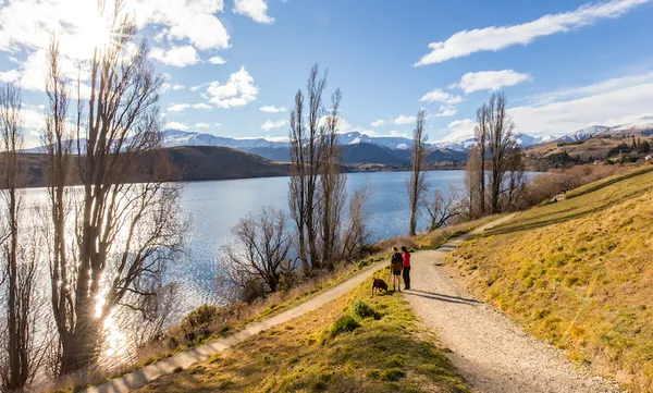 Two people walking a dog at Lake Hayes