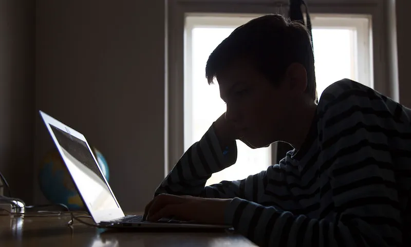 A Boy Sitting At A Laptop