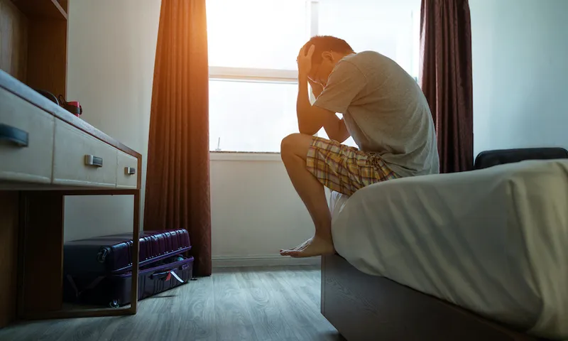 Man sitting on bed with head in hands