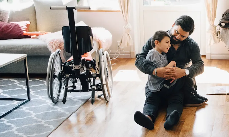 High angle view of father holding autistic son while sitting by daughter on floor at home