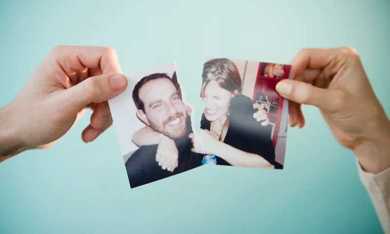 Close up of man’s and woman’s hands holding torn photograph of themselves, studio shot