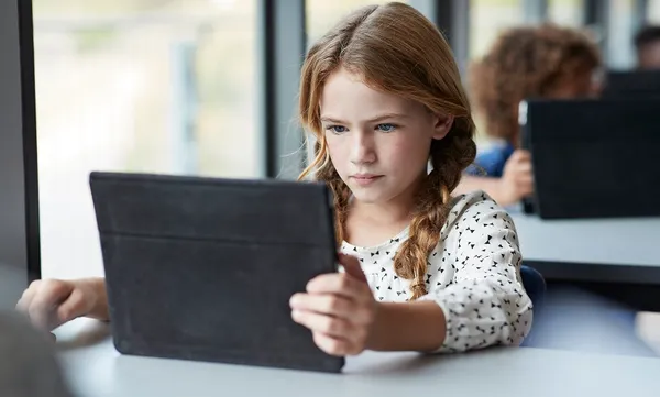 Girl reading on tablet at school