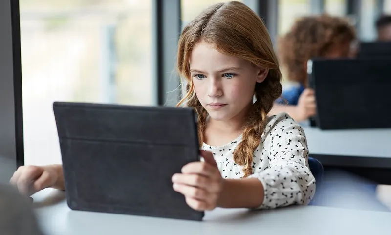 Girl reading on tablet at school