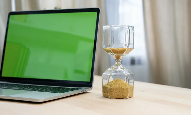 Hourglass on laptop computer concept for time management and countdown to deadline