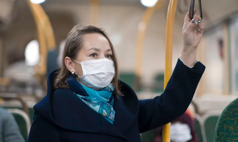 Woman wearing protective medical mask travels in bus