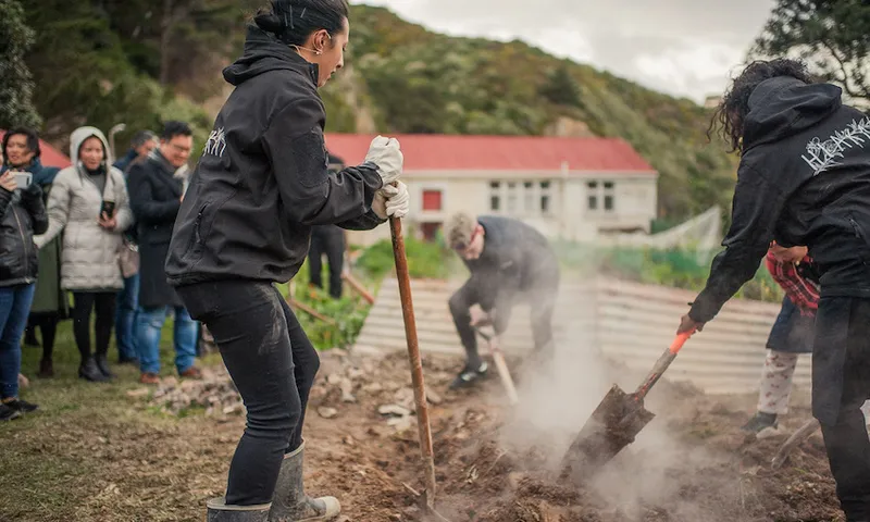 Monique Fiso and others shovelling dirt onto a hangi pit
