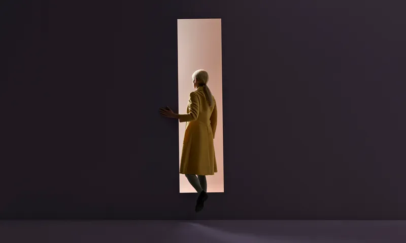 Woman walking into rectangular opening in coloured wall