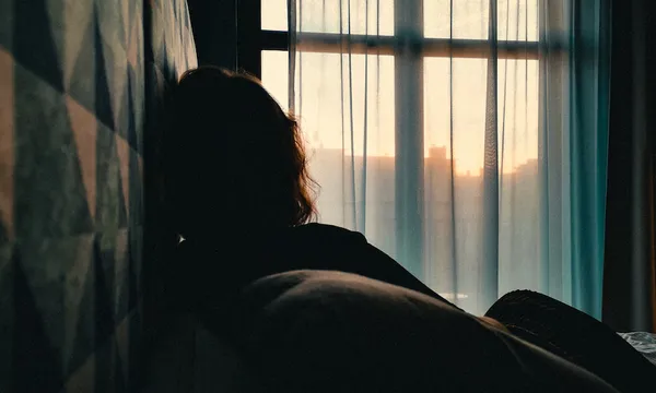 Rear View Of Woman Relaxing On Bed At Home