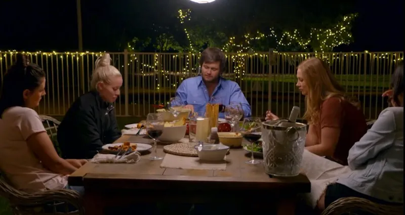 Five people sit at table and eat