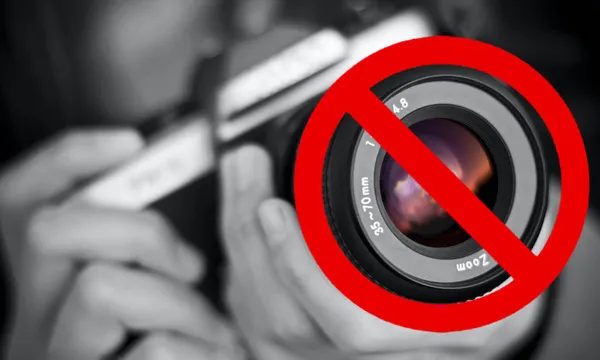 Selectively colored image of a girl holding an old film camera. Shallow focus.