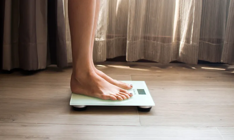 A young woman is weighing herself in a weighing scale