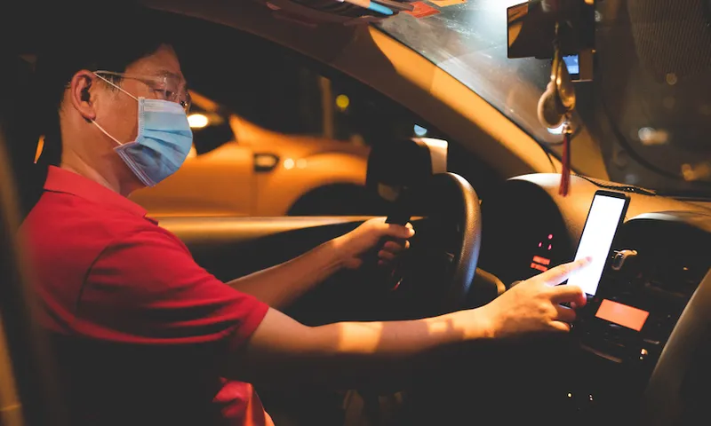 Asian male E-hailing driver with face mask using smartphone