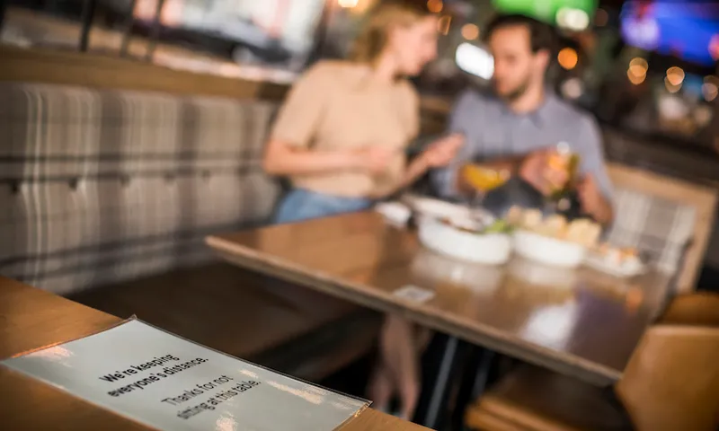 Couple eating in restaurant blurred in background.