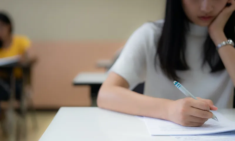School student’s taking exam writing answer in classroom for education and literacy concept