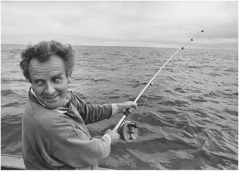 Man grins as he hauls on fishing rod