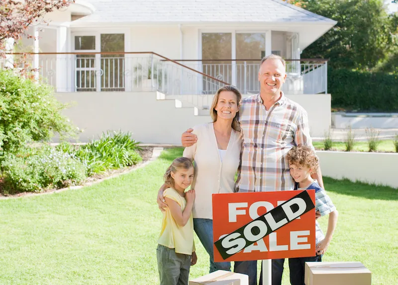 Family standing with sold sign of their new house