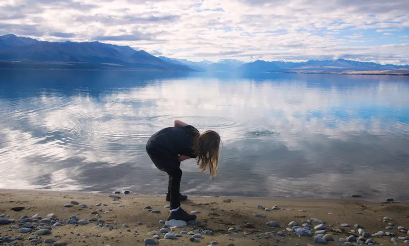 Girl skimming stones at Lake Pukaki, Mount Cook