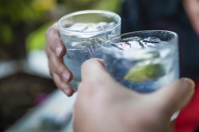 Celebration concept with hand close-up of a couple celebrating the beginning of their vacations with each a gin & tonic.