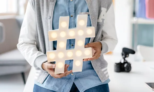 Young woman holding hashtag sign in studio