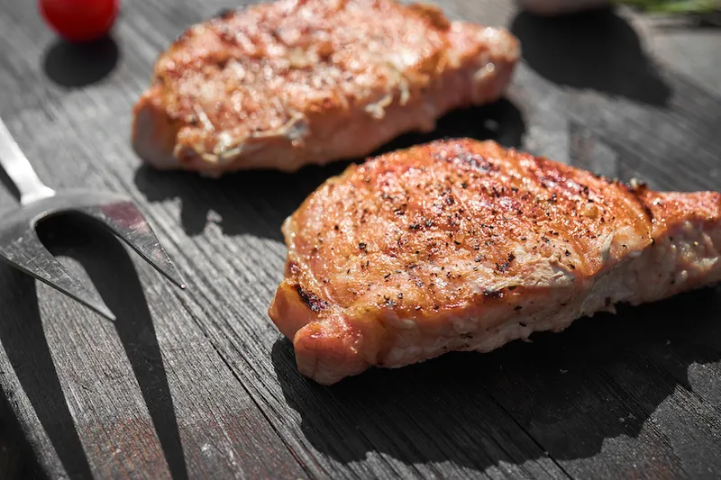 Pork steaks cooking on barbecue grill