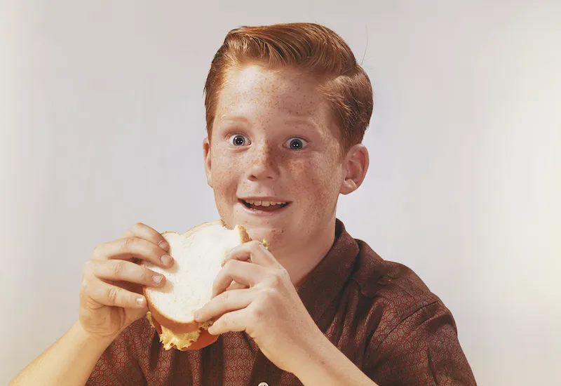 Boy eating sandwich, smiling
