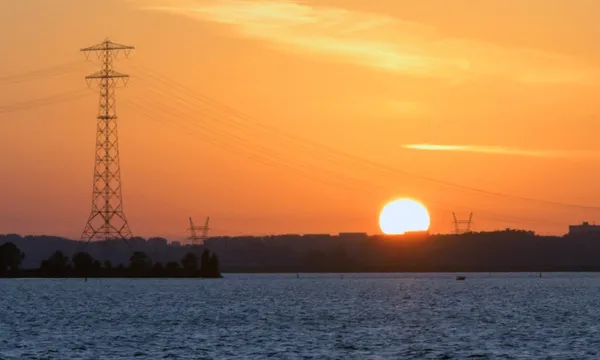 sun powerlines over water generic getty images