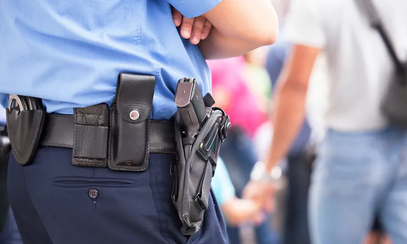 Midsection Of Police With Handgun Standing Outdoors