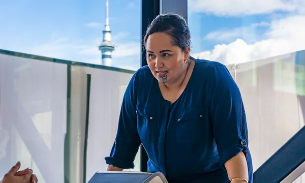 Maori Businesswoman Making a Conference Call With Auckland Skytower Behind