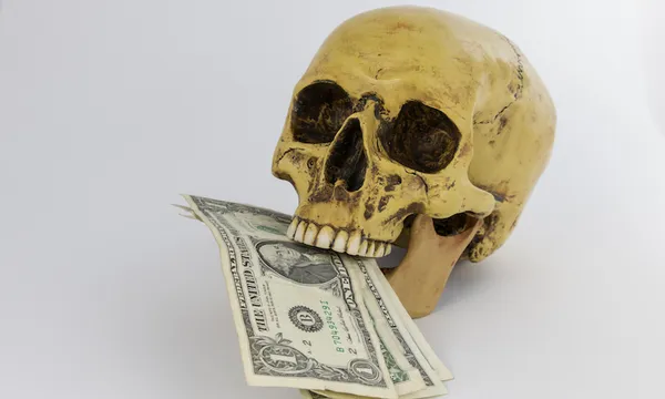Close-Up Of Human Skull With Currency Against White Background