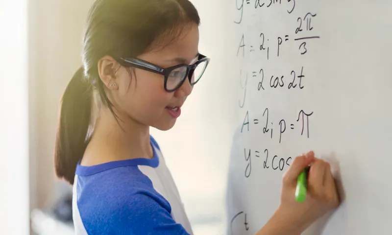 Portrait smiling, confident girl student solving physics equations at whiteboard in classroom