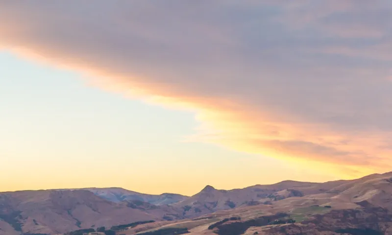 Hiker looking at view at sunrise, Littleton bay, New Zealand