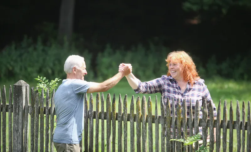 Neighbors greeting each other over fence