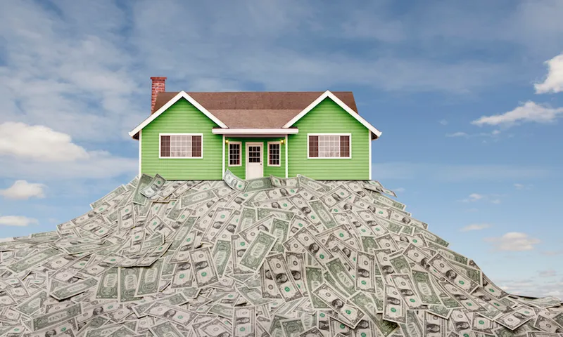 House sitting on pile of dollar bills