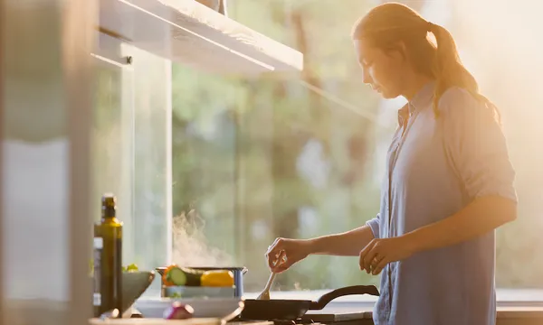 Woman cooking at stove in sunny kitchen