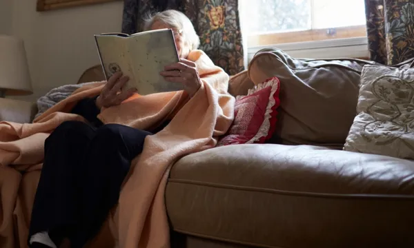 elderly woman reading under blanket getty