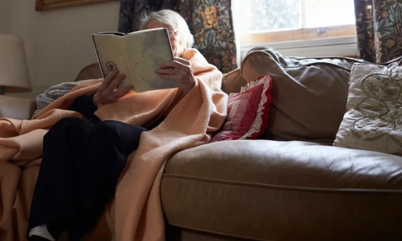 elderly woman reading under blanket getty