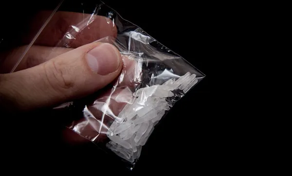 Cropped Image Of Hand Holding Methamphetamine Against Black Background