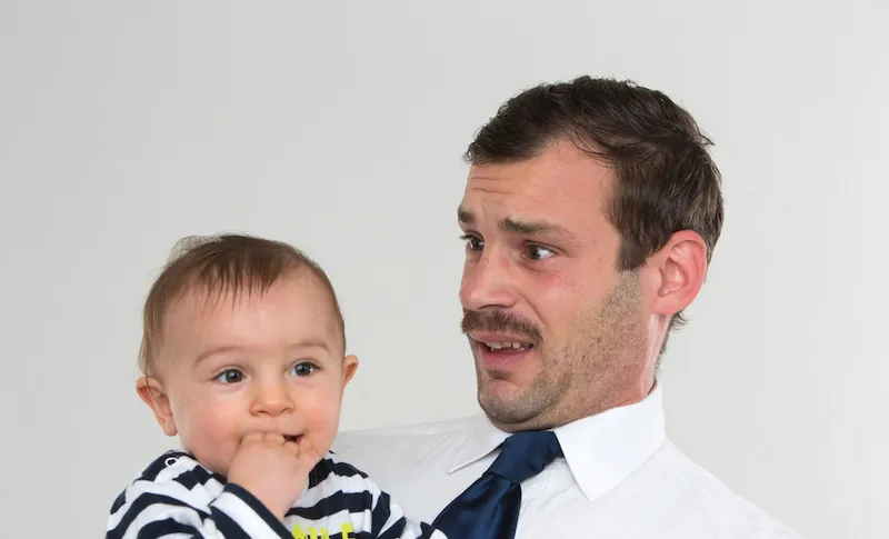 Father Carrying Baby Boy Against White Background