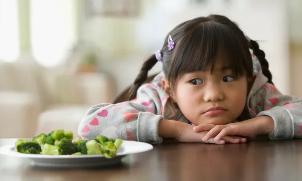 Asian girl looking at broccoli